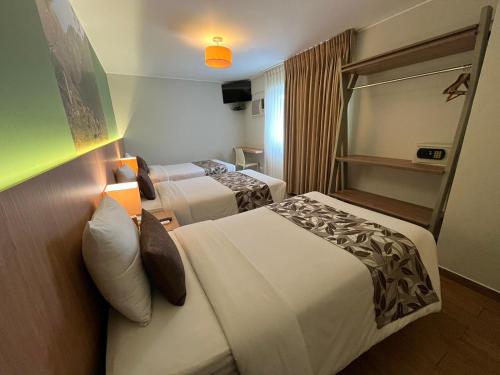 a hotel room with two beds and a television at Hotel El Tambo 2 in Lima