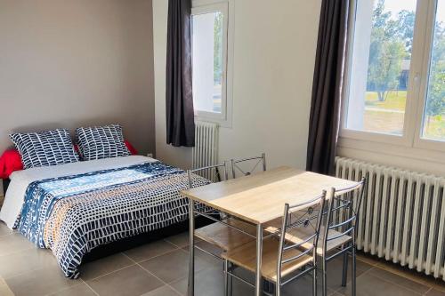 une chambre avec un lit, une table et une fenêtre dans l'établissement Logement fonctionnel à l'entrée de Bordeaux, à Carbon-Blanc