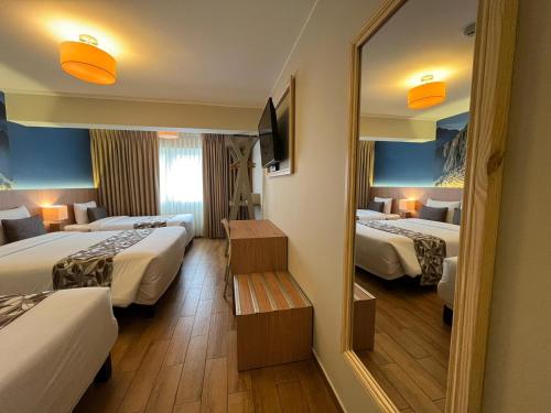 a hotel room with two beds and a mirror at Hotel El Tambo 2 in Lima