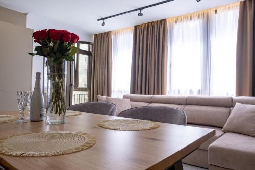 a living room with a table with a vase of roses at Apartment PREMIUM CALPE in Ifach