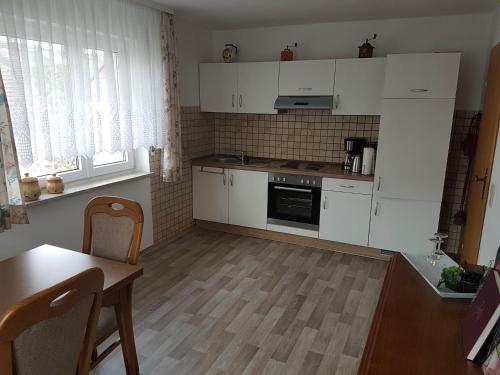 a kitchen with white cabinets and a table and a table and chairs at Haus Weinbergblick in Markelsheim