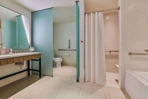 a bathroom with a shower and a sink and a toilet at Virgin Hotels Las Vegas by Suiteness in Las Vegas