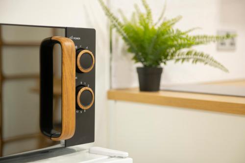 a microwave with a wooden handle next to a plant at Small Studio Arnold Nottingham in Nottingham