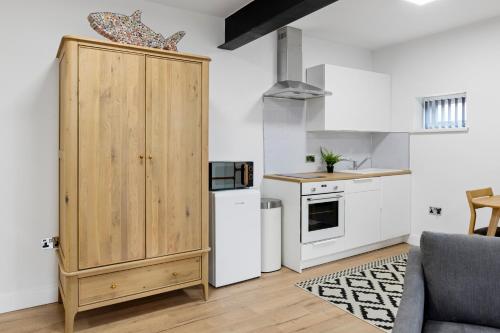 a kitchen with a large wooden cabinet next to a refrigerator at Small Studio Arnold Nottingham in Nottingham