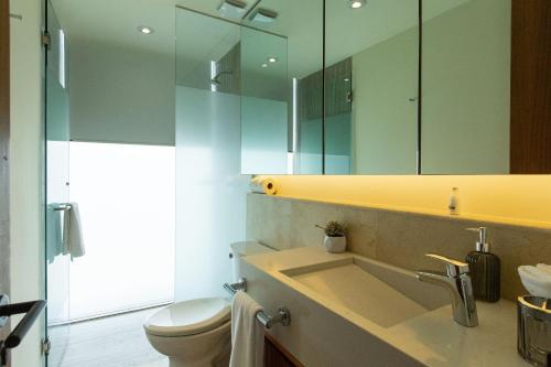 a bathroom with a sink and a toilet and a mirror at Beachfront|Pool|Gym Beautiful Studio Zantamar 303D in Cruz de Huanacaxtle