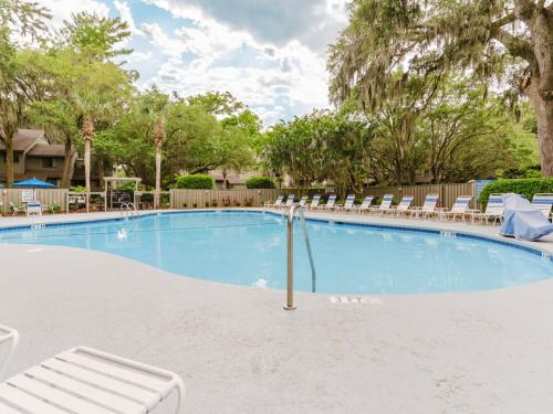 a large swimming pool with lounge chairs and trees at Southwind II at Shipyard in Hilton Head Island