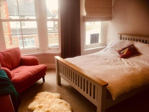a bedroom with a bed and a chair and a window at Cosy Roath home near the park in Cardiff