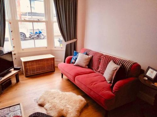 a living room with a red couch and a window at Cosy Roath home near the park in Cardiff