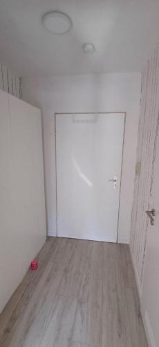 an empty room with a white door and a wooden floor at Apartment Blätterwald in Bad Sachsa