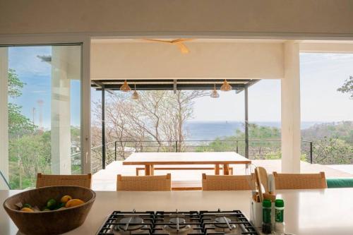 a kitchen with a stove top oven next to a table at Casa Deriva - Modern 3 Bedroom AC with Pool in Playa Maderas