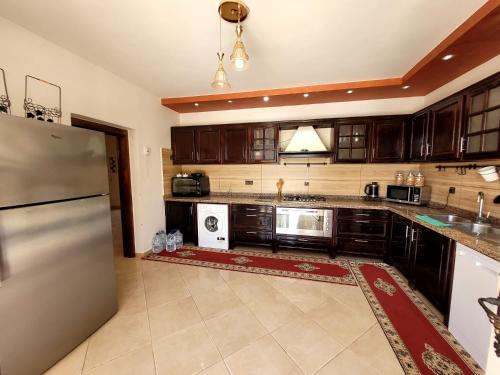 a kitchen with wooden cabinets and a stainless steel refrigerator at Villa Al Jaouhara in Essaouira