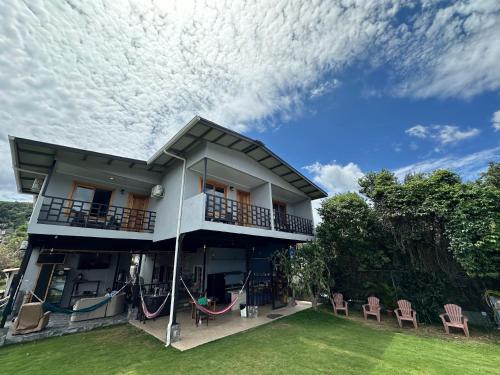 a house with a balcony and chairs on the lawn at Blasina Beer Hostel in Boquete