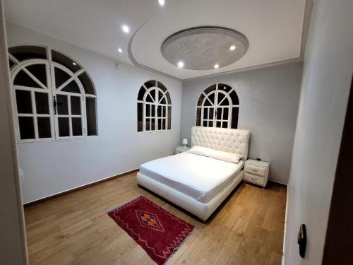 a bedroom with a white bed and two windows at Villa Al Jaouhara in Essaouira
