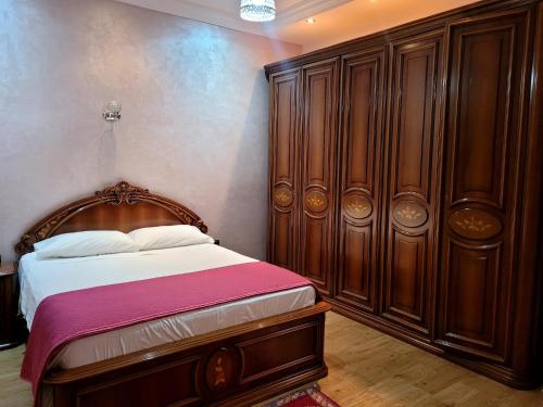 a bedroom with a bed and a large wooden cabinet at Villa Al Jaouhara in Essaouira