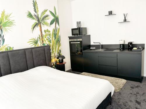 a bedroom with a white bed and a kitchen at Studio People - N4 in Alençon