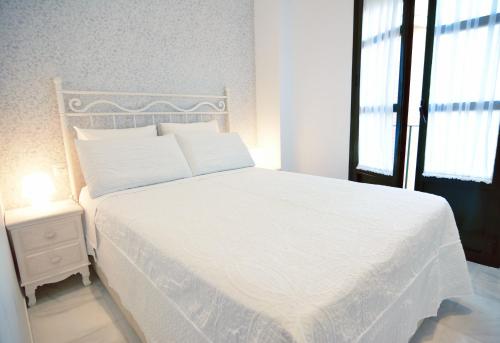um quarto com uma cama branca e uma janela em Macarena Home em Sevilha