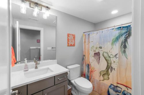 a bathroom with a toilet and a sink and a shower curtain at Port Place Paradise in Ottawa