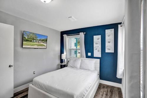 a bedroom with a white bed and a blue wall at Luxury Miami Retreat in North Miami