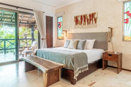 a bedroom with a bed and a wooden bench at Casa de Los Vientos Soliman Bay in Tulum