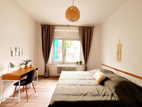 een slaapkamer met een bed, een bureau en een raam bij Stillvolle Stadtwohnung am Klinikum Bielefeld, zentral und mit Parkplatz! in Bielefeld