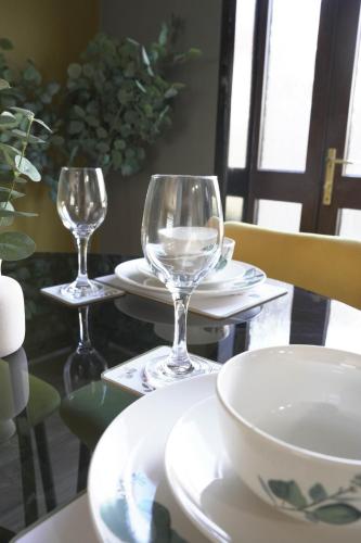 a table with two wine glasses and plates on it at Ten Acres House in Sauchie