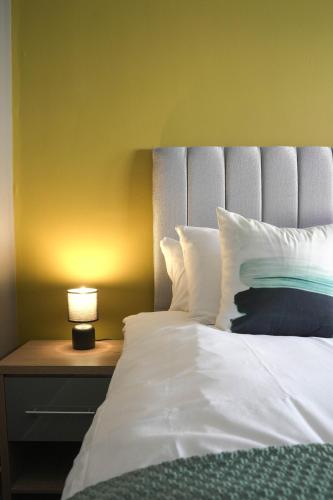 a bedroom with a white bed with a lamp on a table at Ten Acres House in Sauchie