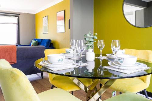 a dining room with a glass table and yellow chairs at Ten Acres House in Sauchie