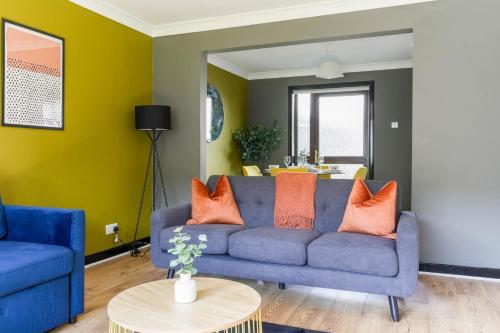 a living room with a blue couch and orange pillows at Ten Acres House in Sauchie