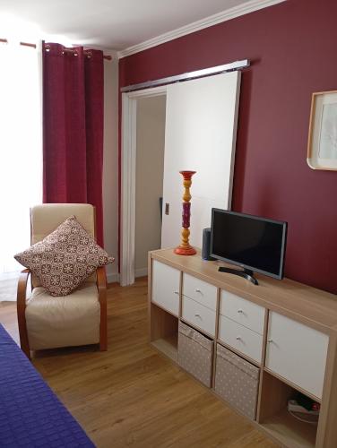 a living room with a television and a chair at Aliciamar E by Casas de Setúbal in Setúbal