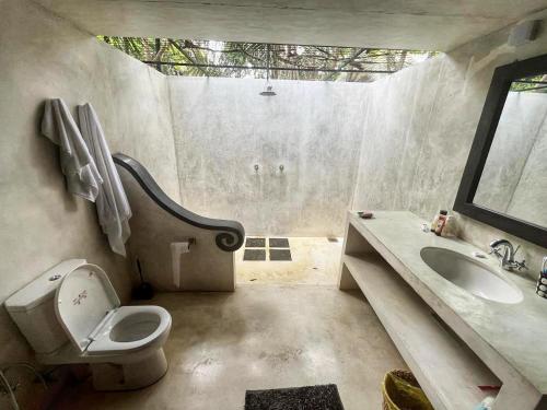 a bathroom with a toilet and a sink at Namaskara by the Beach - Charming Beachfront Bungalow Retreat in Moraketiara