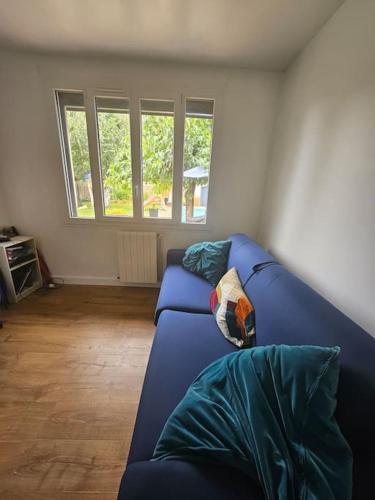 - un canapé bleu dans le salon avec fenêtres dans l'établissement Maison avec piscine Bordeaux Merignac 33, à Mérignac