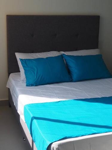 a bed with blue pillows on top of it at Apartamento Casa Garzon in Girardot