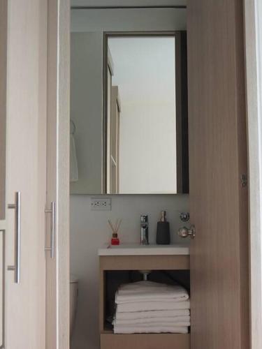a bathroom with a mirror and a pile of towels at Apartamento Casa Garzon in Girardot