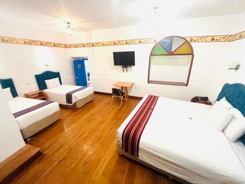 a hotel room with two beds and a tv at Rojas Plaza Boutique in Cusco