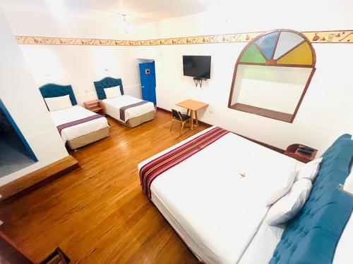a hotel room with two beds and a tv at Rojas Plaza Boutique in Cusco