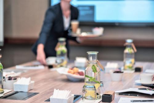 a table with a bottle of water and a person in the background at Al Messila, A Luxury Collection Resort & Spa, Doha in Doha