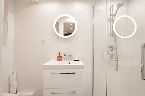une salle de bain blanche avec un lavabo et une douche dans l'établissement Seine - Best localisation - Bail mobilité, à Paris
