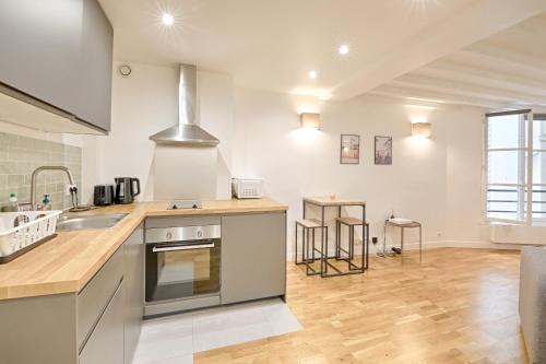 une cuisine avec un évier et une cuisinière four supérieur dans l'établissement Seine - Best localisation - Bail mobilité, à Paris