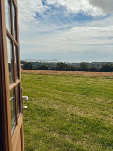 a view of a field from a open door at Barrel Cabin 1 in St Austell