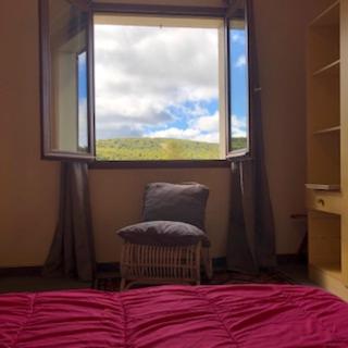 une chambre avec un lit et une fenêtre avec une chaise dans l'établissement Fraîcheur , forêt d'Aubrac , au coeur de la nature, à Prades-dʼAubrac