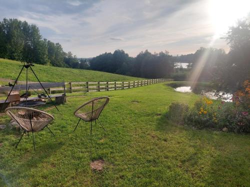 two chairs sitting in a field next to a river at Pausa in Żegoty