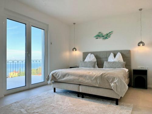 a bedroom with a large bed and a large window at Villa Lula, Pool, Sauna, 6 Personen, 3 Bäder in Dobreć