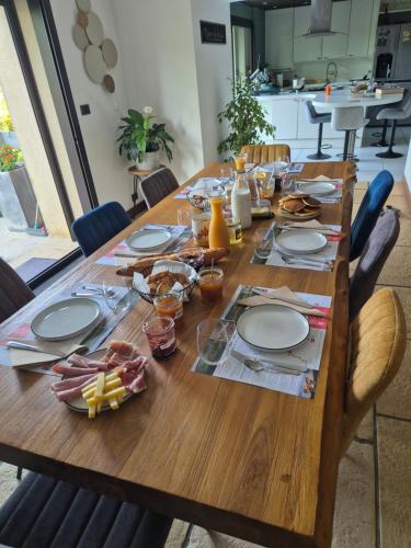 Au Lavoir du Serein "La Billaude" et "La Langouette" في Saint-Germain-lès-Arlay: طاولة خشبية عليها لوحات وطعام