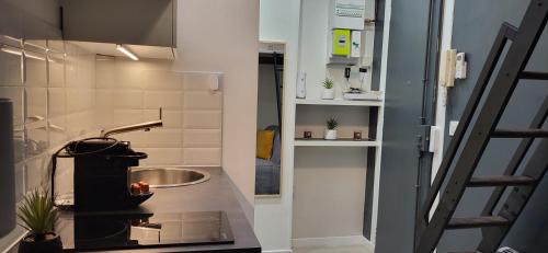 une petite cuisine avec un évier et une cuisinière dans l'établissement Chambre à Paris avec ASCENSEUR !, à Paris
