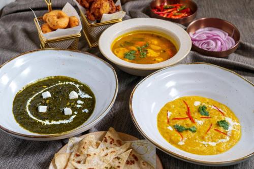 a table topped with bowls of soup and other foods at Hotel Indigo Bangkok Wireless Road by IHG in Bangkok