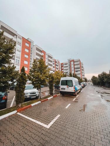 a van parked in a parking lot next to tall buildings at Cozy Apartment in Gjilan in Gjilan