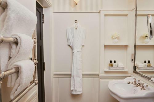 a bathroom with a sink and a robe hanging on a door at At Sloane in London