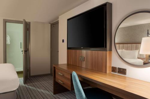 a room with a desk with a tv and a mirror at DoubleTree by Hilton London Chelsea in London