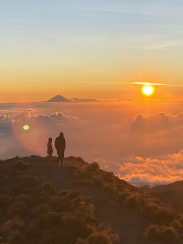 two people standing on top of a mountain watching the sunset at Coconut Homestay Tetebatu in Tetebatu