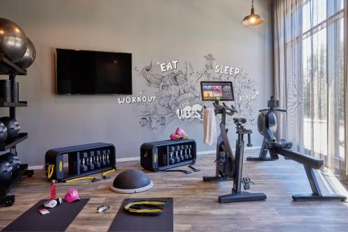 a gym with exercise equipment and a wall with graffiti at Moxy Cologne Muelheim in Cologne